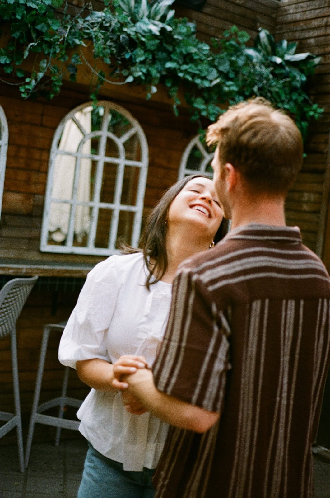 couple laughing on the patio of a cocktail bar during their film engagement session in little italy